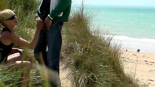 Slender blonde milf gives a wonderful handjob on the beach
